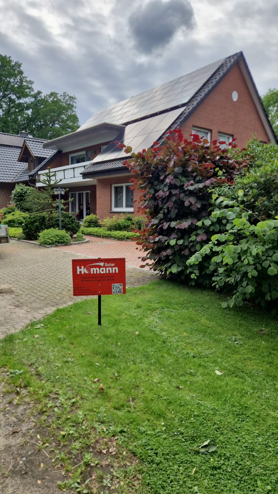 Bauschild von Homann Solar vor einem Haus mit PV-Anlage in Lingen